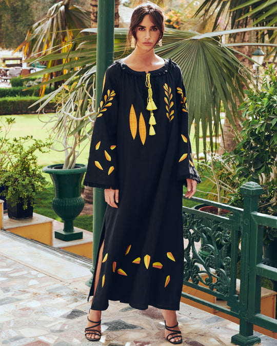 Black linen kaftan maxi dress with yellow and orange leaf embroidery, angel sleeves with frayed trim and tassel ties, lifestyle view - Zalxndra Resort