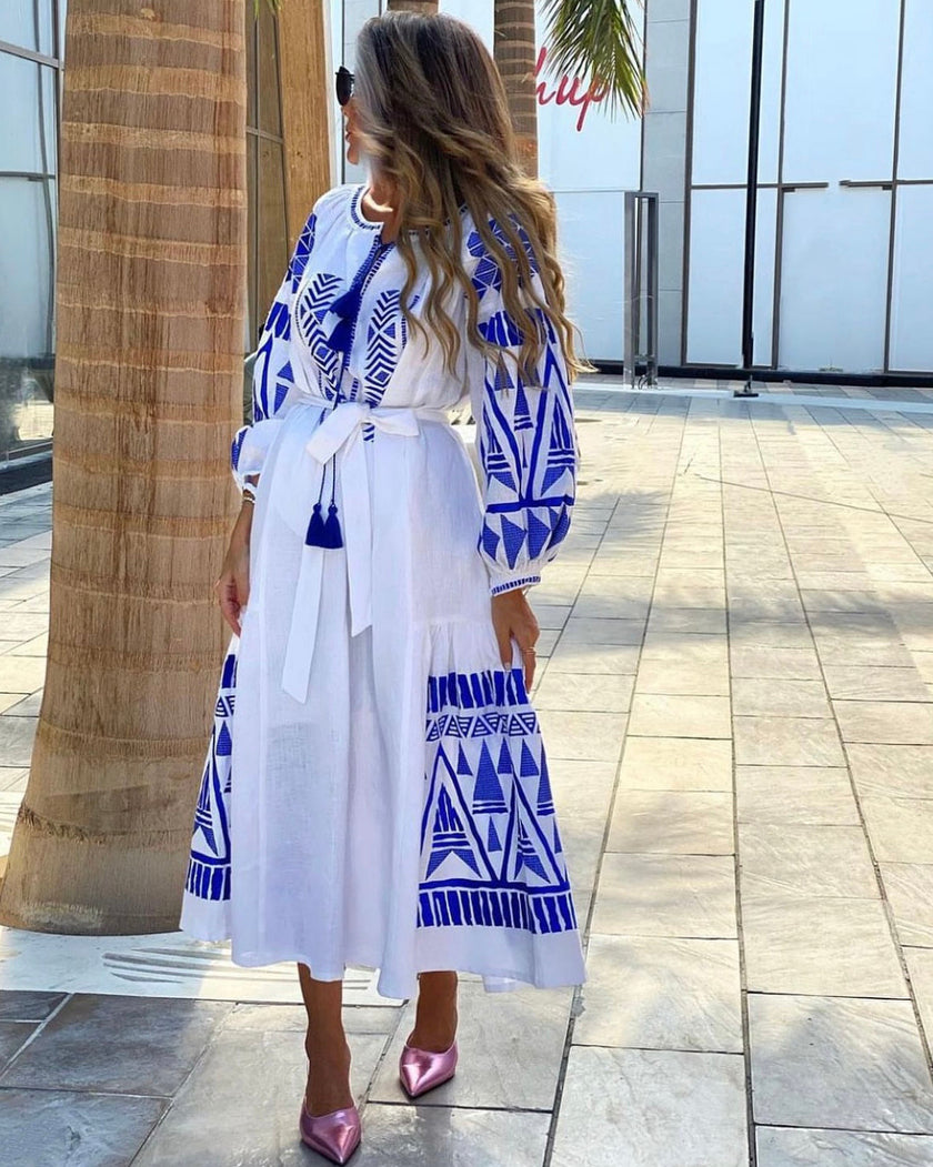 White linen kaftan maxi dress with blue geometric embroidery, balloon sleeves, tassel ties and self-tie belt, lifestyle back view - Zalxndra Resort