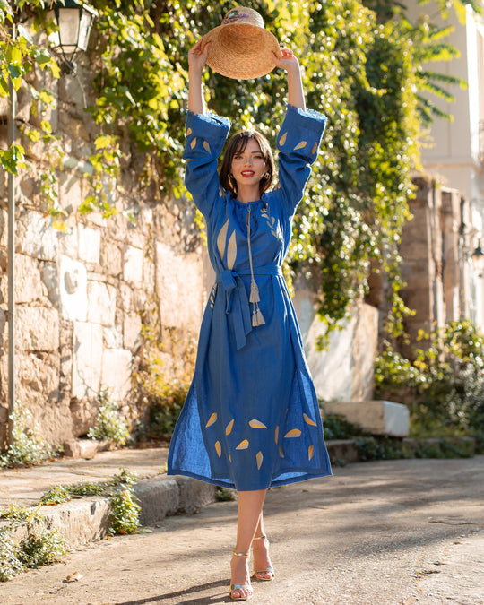 Royal blue linen kaftan maxi dress with gold leaf embroidery, angel sleeves and tassel tie belt, styled with straw hat, lifestyle view - Zalxndra Resort