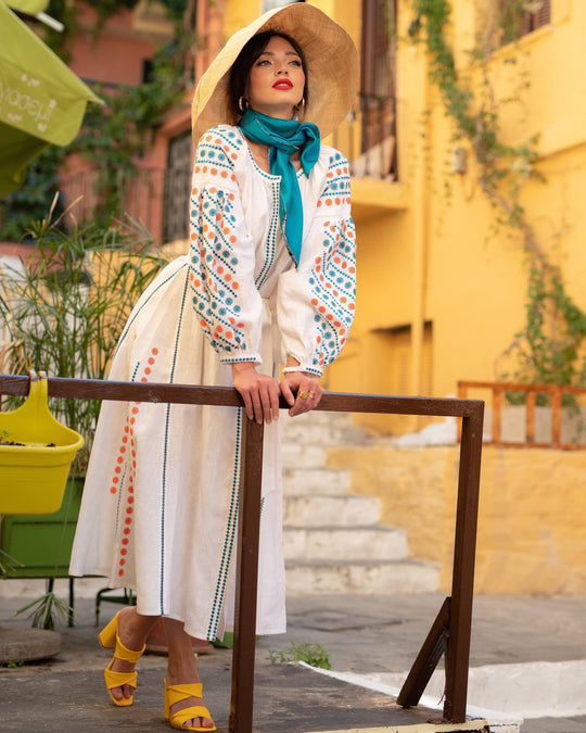 Model in white linen kaftan maxi dress with teal and orange embroidery and balloon sleeves on Mediterranean street - Zalxndra Resort