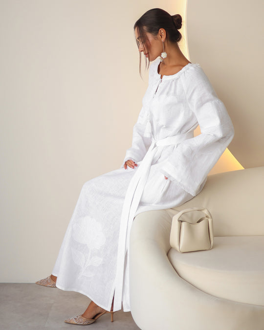 Seated view of white linen kaftan maxi dress with tonal floral embroidery and frayed bell sleeves - Zalxndra Resort
