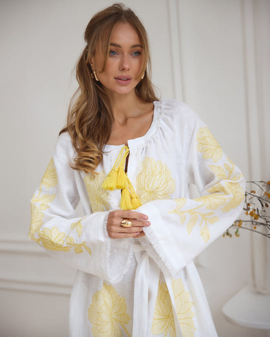 Bodice detail of white linen kaftan maxi dress with yellow floral embroidery, frayed angel sleeves, and tassel tie - Zalxndra Resort